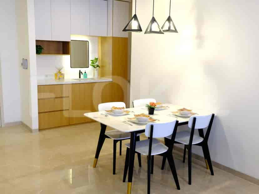 Area makan modern dengan meja persegi panjang, kursi, dan lampu gantung.