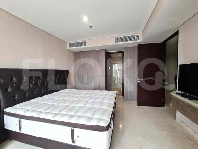 A spacious master bedroom featuring a large bed, a wardrobe, and a view of a doorway.