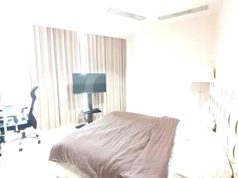 Kamar tidur yang terang dengan tempat tidur dan TV.