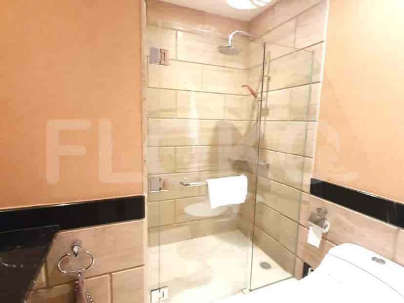 Kamar mandi dengan pancuran kaca, ubin batu, dan desain kontemporer.