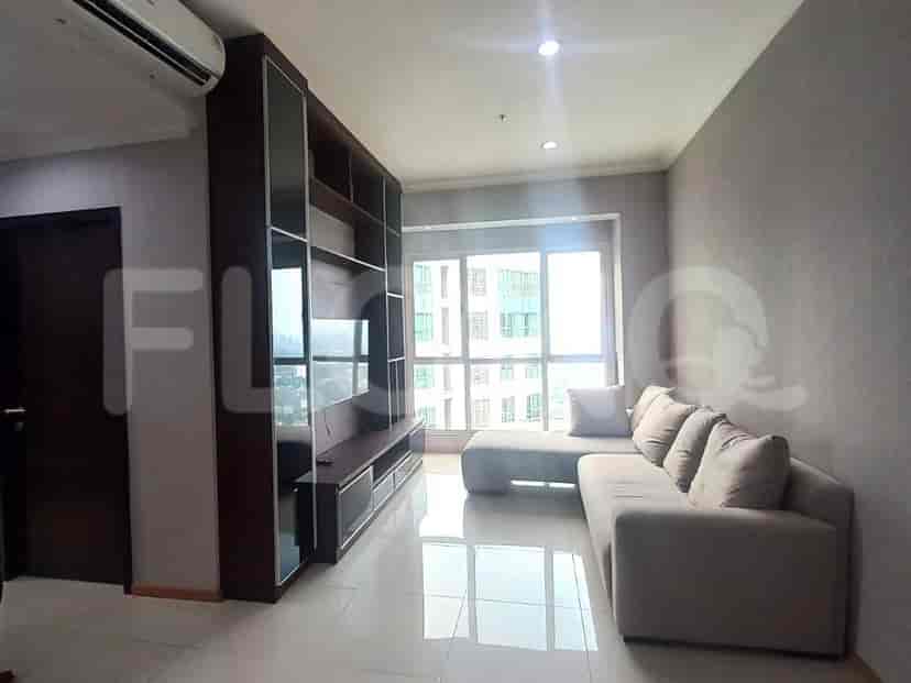 A modern living room featuring a large L-shaped sofa, a built-in entertainment center with a TV, and a large window overlooking a city view.