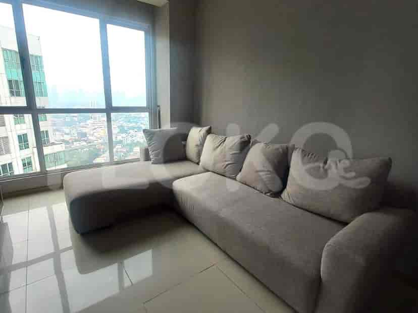 Close-up of the L-shaped sofa in the living room, showing the city view through the window.