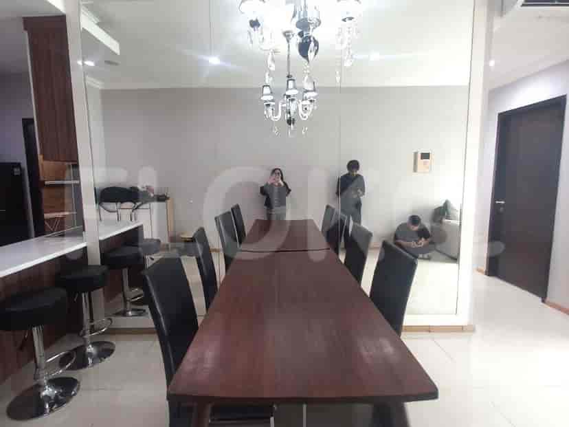 A modern dining area featuring a long dining table and chairs with a chandelier.