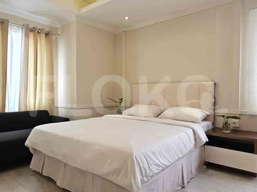 Kamar tidur dengan tempat tidur dengan sandaran kepala, sofa, gorden, dan meja samping.