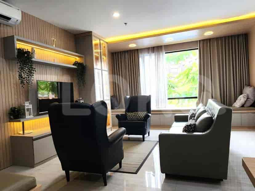 Ruang tamu modern dengan sofa abu-abu tua, dua kursi berlengan hitam, dan TV yang dipasang di dinding.