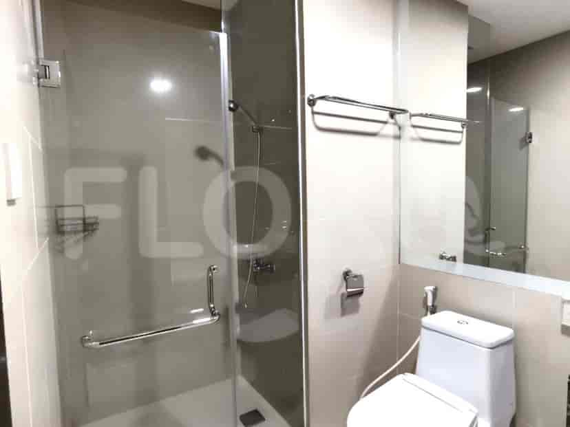 A modern bathroom with a glass shower, a toilet, and a large mirror.