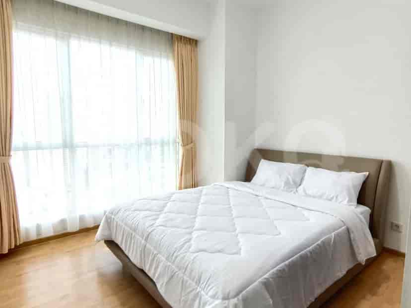 A second bedroom with a bed, large windows, and neutral decor.