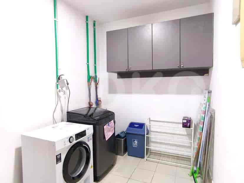 A laundry room with a washing machine, dryer, and storage cabinets.