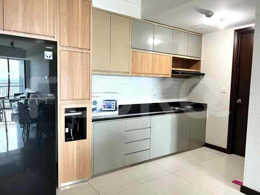 A modern kitchen featuring wooden cabinets, a black fridge, and a cooking area.