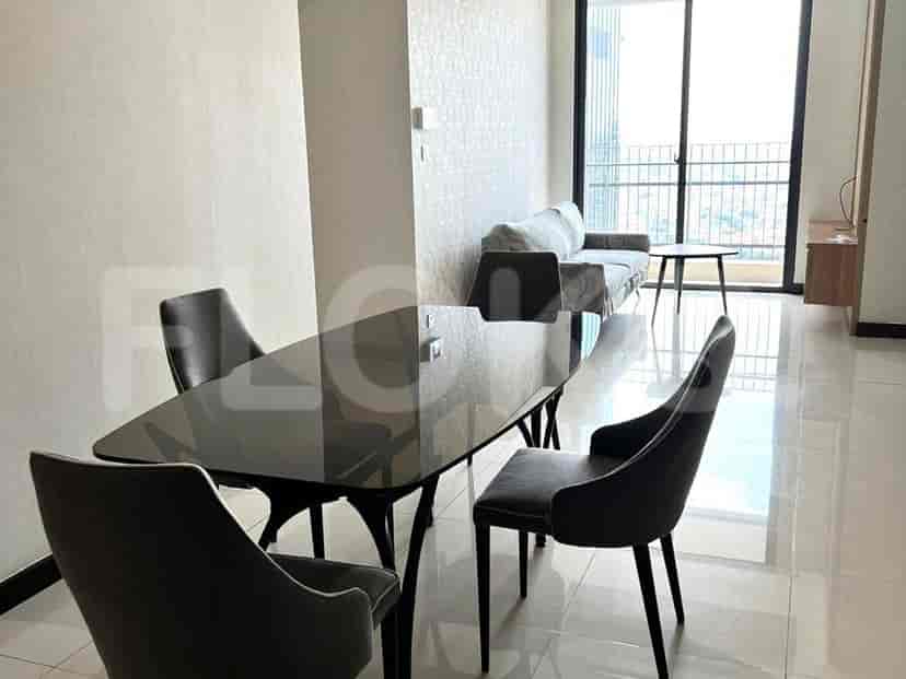 Modern dining area with a black glass dining table and four chairs, along with a sofa and a round coffee table in the background.