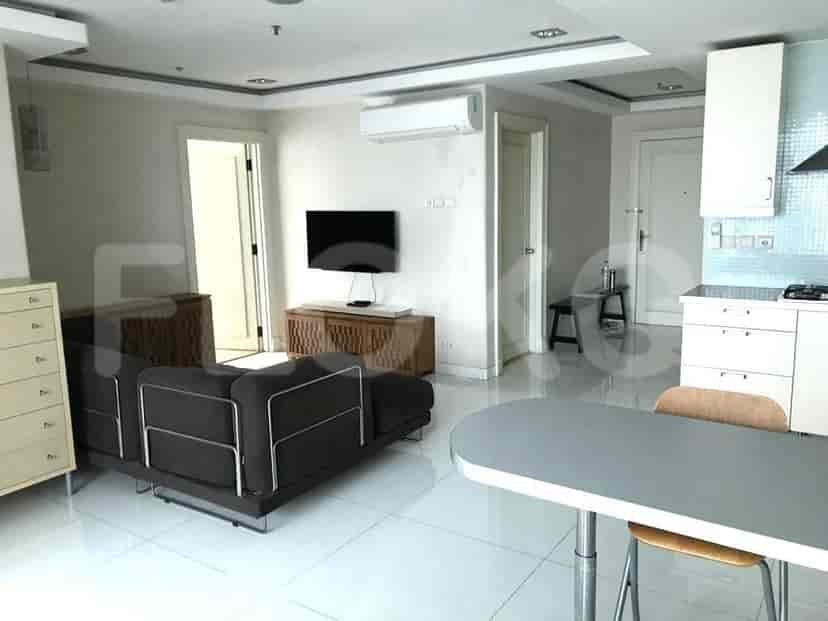 A modern living room featuring a dark grey sofa, TV, and a dining area with a table and chairs.