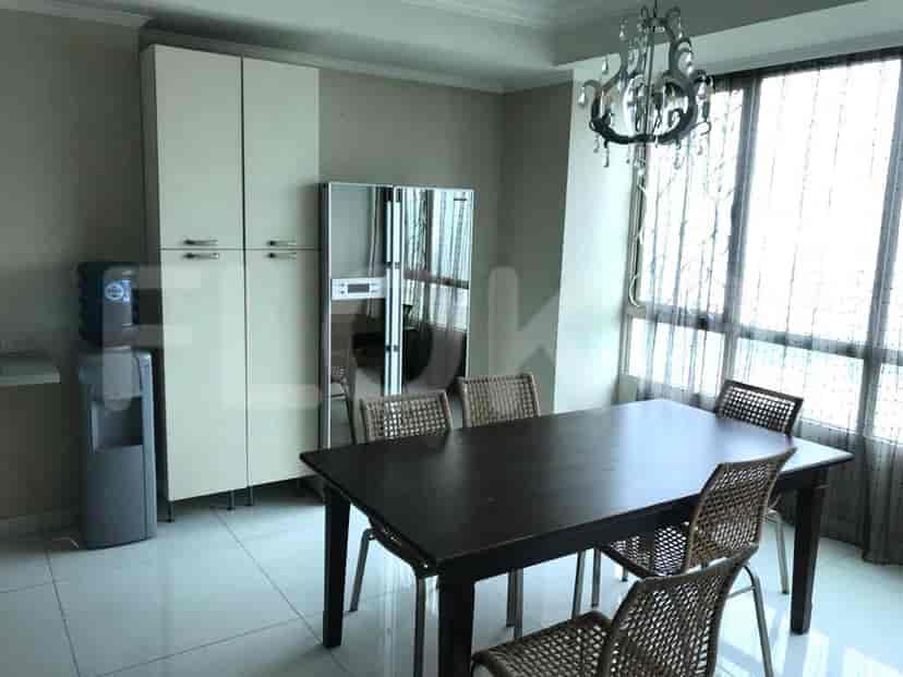 A dining room setup with a table, chairs, a refrigerator, and a water cooler.