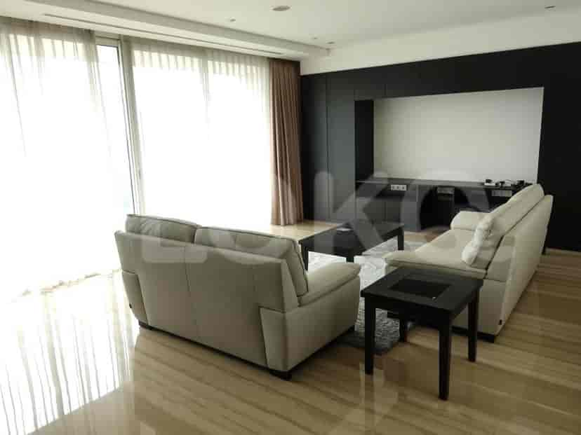 Spacious living room with an L-shaped grey sofa, smart TV, and large window with sheer curtains.