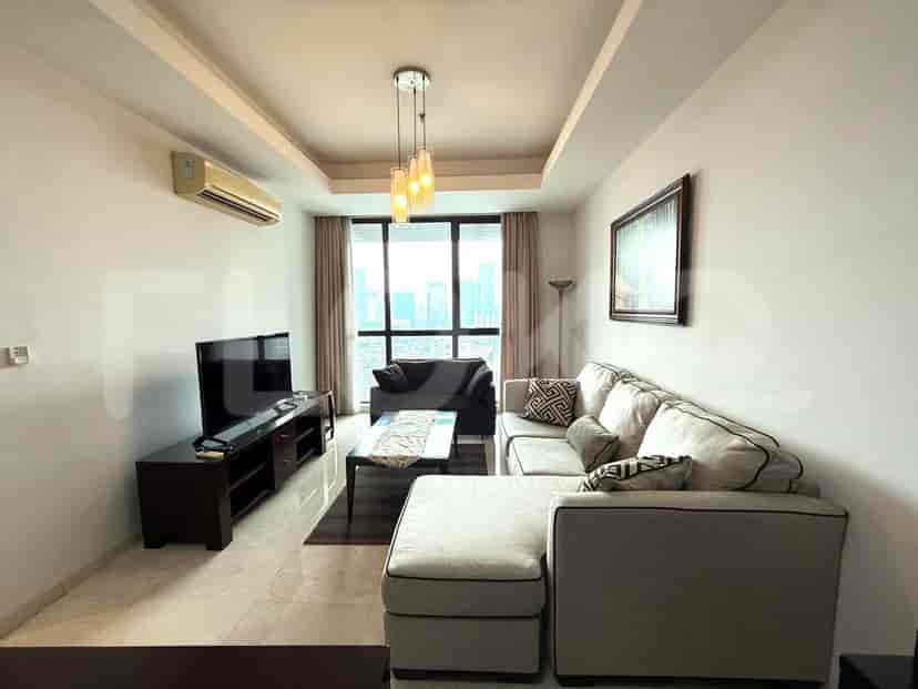A modern living room featuring a grey L-shaped sofa, a dark wood TV stand, and a large window with city views.