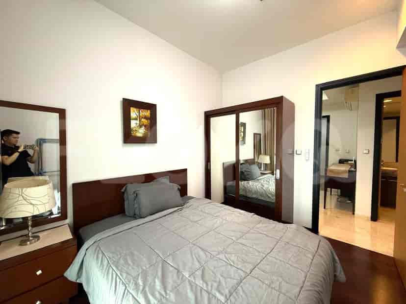 A bedroom with a queen-sized bed, a large mirror, and a wooden wardrobe with sliding doors.
