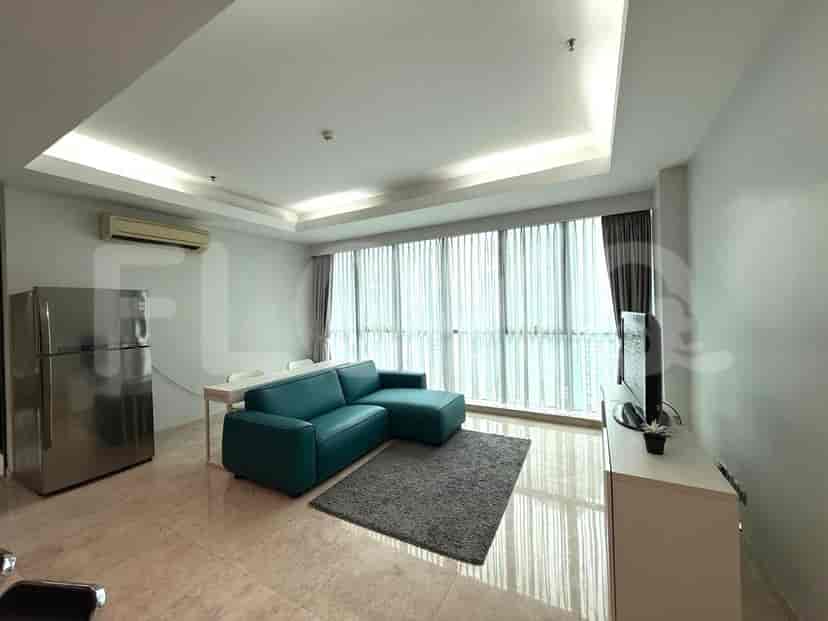 A modern living room with an L-shaped teal sofa, a wall-mounted TV, and large windows.