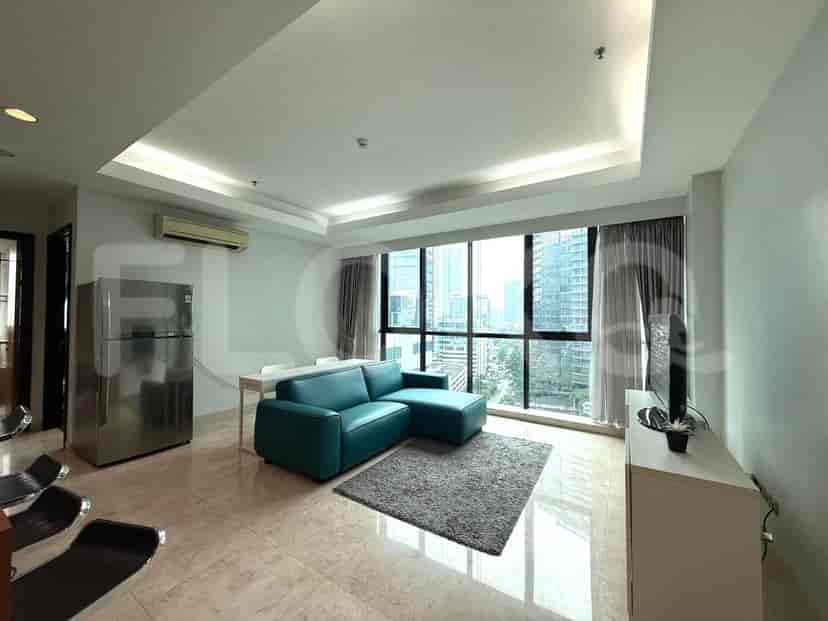Living room with a large window offering a city view, teal sectional sofa, and a TV.