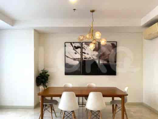A dining area with a wooden table, white chairs, and a decorative light fixture.