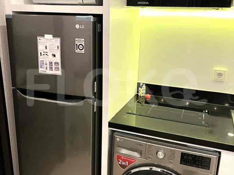 Modern kitchenette with stainless steel appliances, including a refrigerator and washing machine.