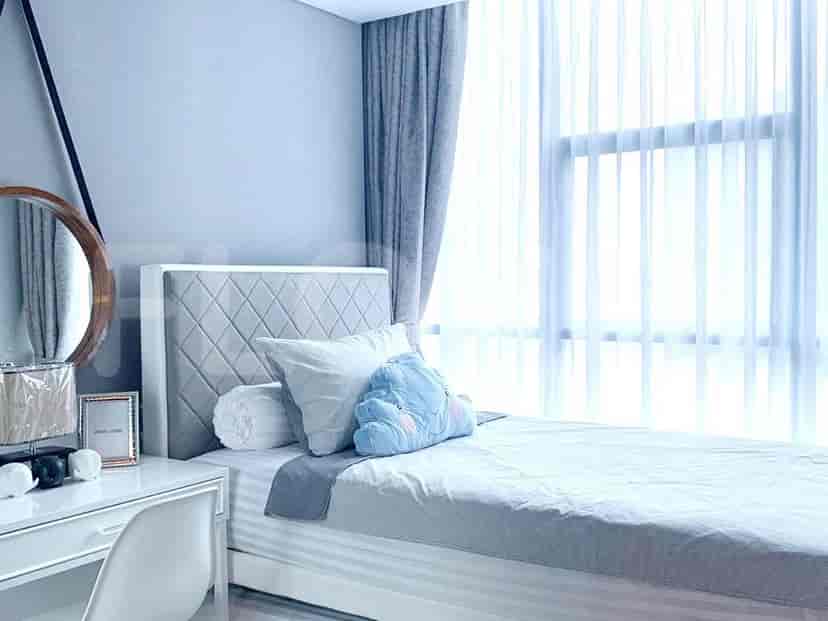 A bedroom with a bed, vanity, and a large window.