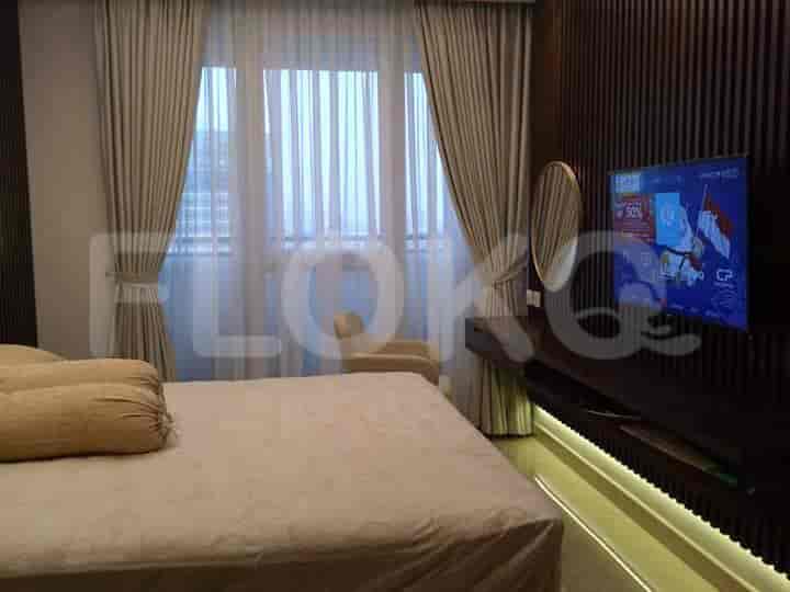 A bedroom with a bed, TV, and curtains.