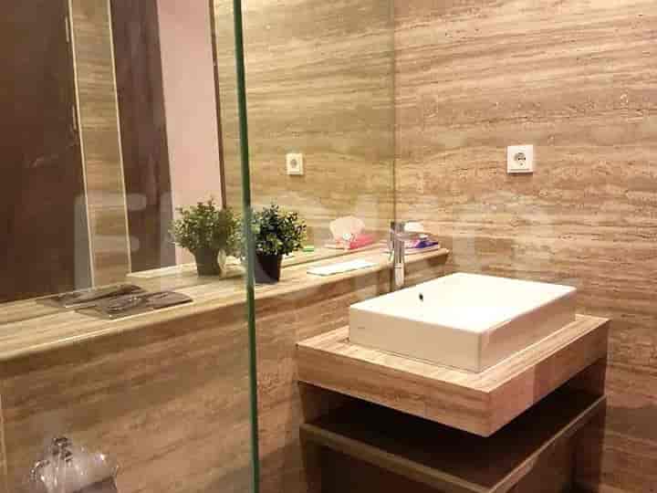 Bathroom with a modern sink, marble walls, and a glass-enclosed shower.