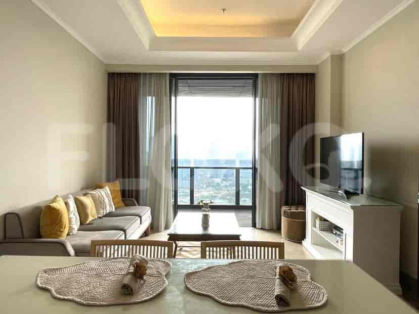 A bright living room with a grey sofa, TV, and a view of the city.