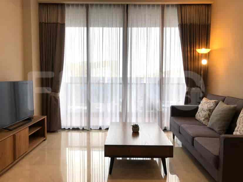 Living room with a sofa, TV, and large windows with curtains.