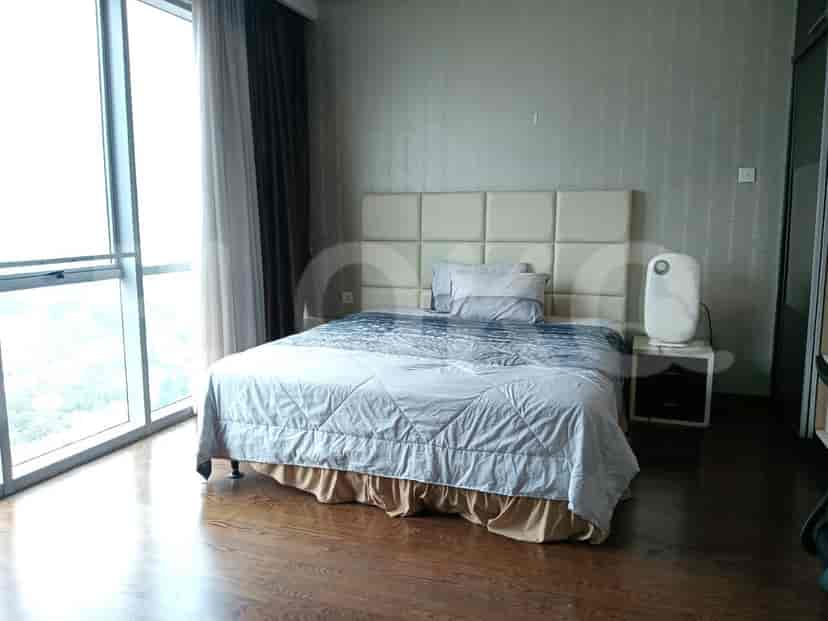 A spacious bedroom with a bed, large window, and wooden floors.