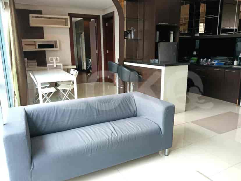 A modern living room with a grey sofa, a dining table and a kitchen.