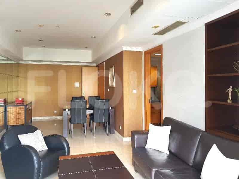 A well-lit living and dining space with a dining table, sofa, and a door leading to the kitchen.