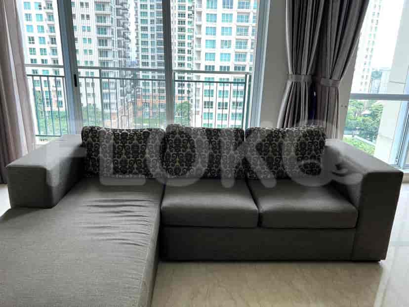 A modern living room featuring a large sectional sofa with patterned cushions, positioned in front of a floor-to-ceiling window.