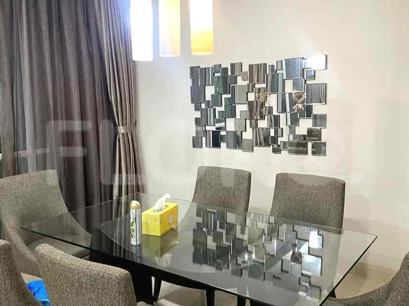 A dining area featuring a glass-top dining table with seating for six, complemented by an abstract mirrored wall art.
