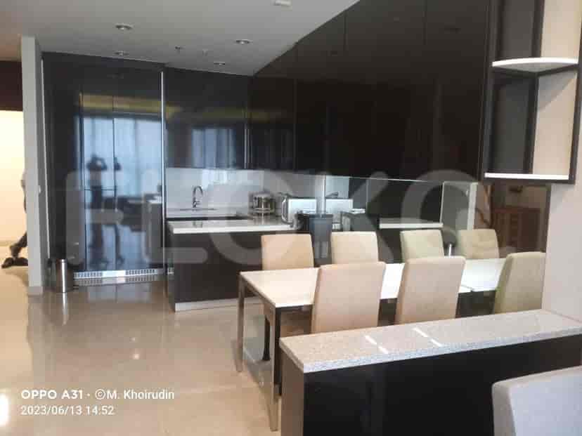 Elegant dining area with a white table and black cabinetry, adjoining an open kitchen.
