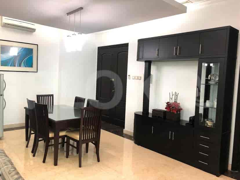 A dining room with a glass-top table, dark wood chairs, and built-in storage.