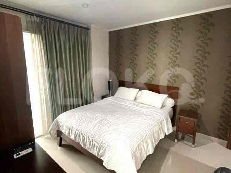 A bedroom with a bed, nightstands, and patterned wallpaper.
