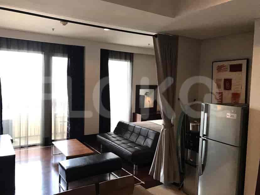 A combined living room and bedroom area with a sofa, a bed, and large windows.