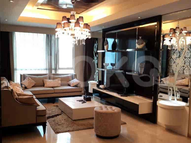 Ruang tamu mewah dengan sofa besar, unit hiburan, dan lampu gantung.