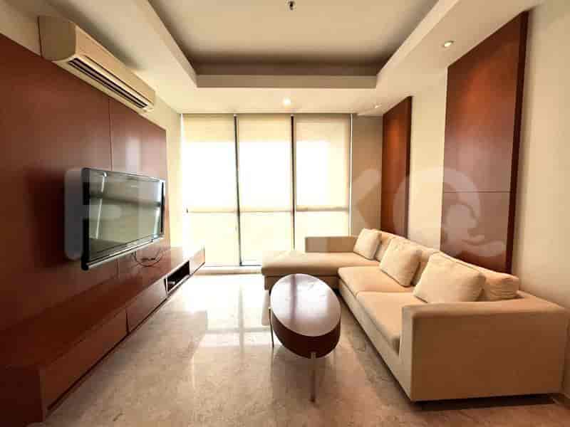 A modern living room featuring a large L-shaped sofa, wall-mounted TV, and natural light from a large window.