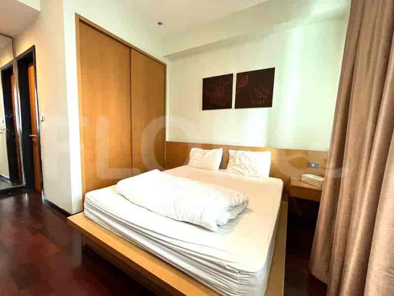 A bedroom featuring a wooden bed frame, a large closet, and artwork on the wall.