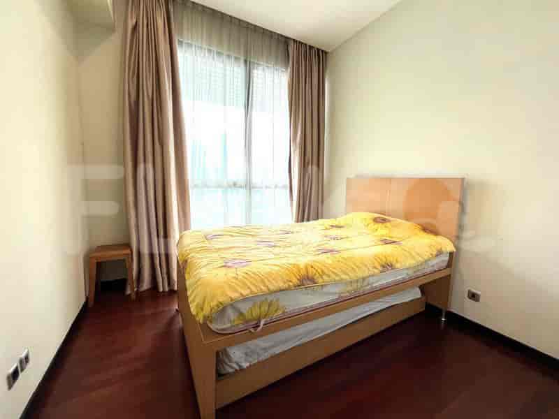 A bedroom with a single bed, a wooden bed frame, and a large window with curtains.