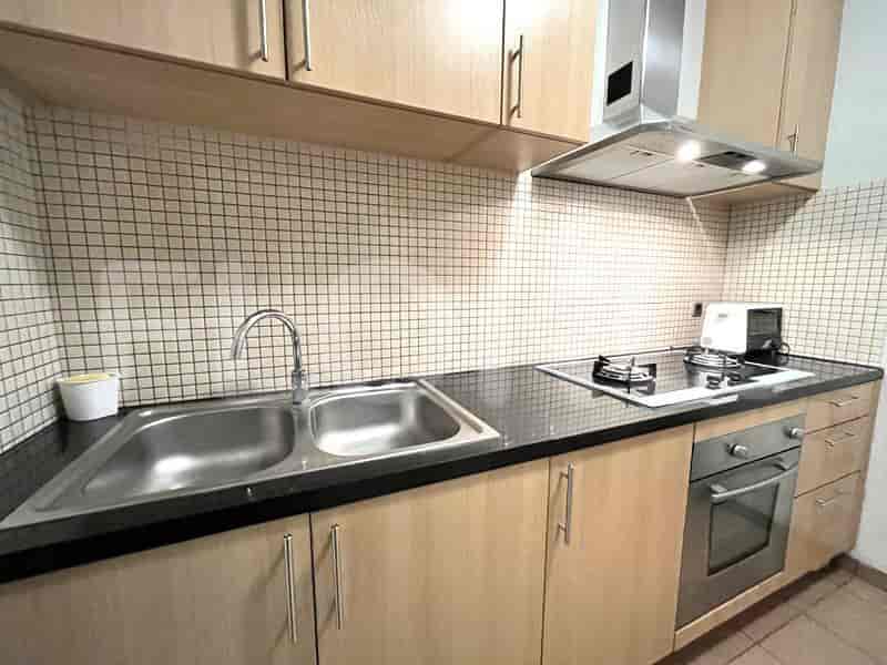 A modern kitchen with wooden cabinets, a double sink, and a gas stove.