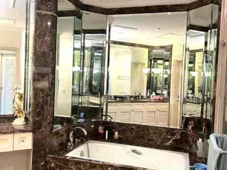 Kamar mandi mewah yang menampilkan bak mandi dengan aksen marmer dan cermin besar.