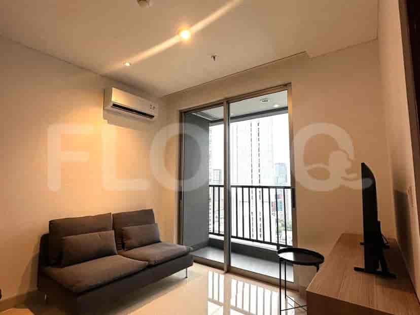 Living room with a gray sofa, TV, and a balcony with city view.