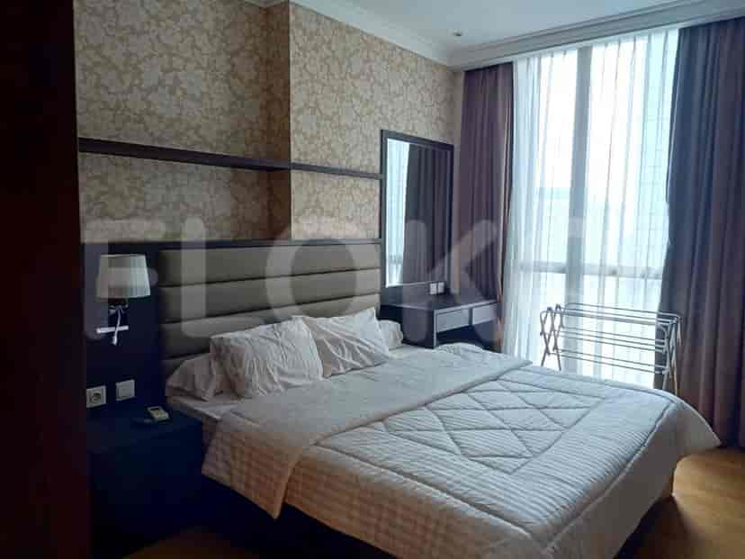 A bedroom with a large bed, window with curtains, and a vanity.