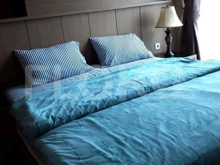 A bedroom with a blue-colored bedding and a bedside lamp.