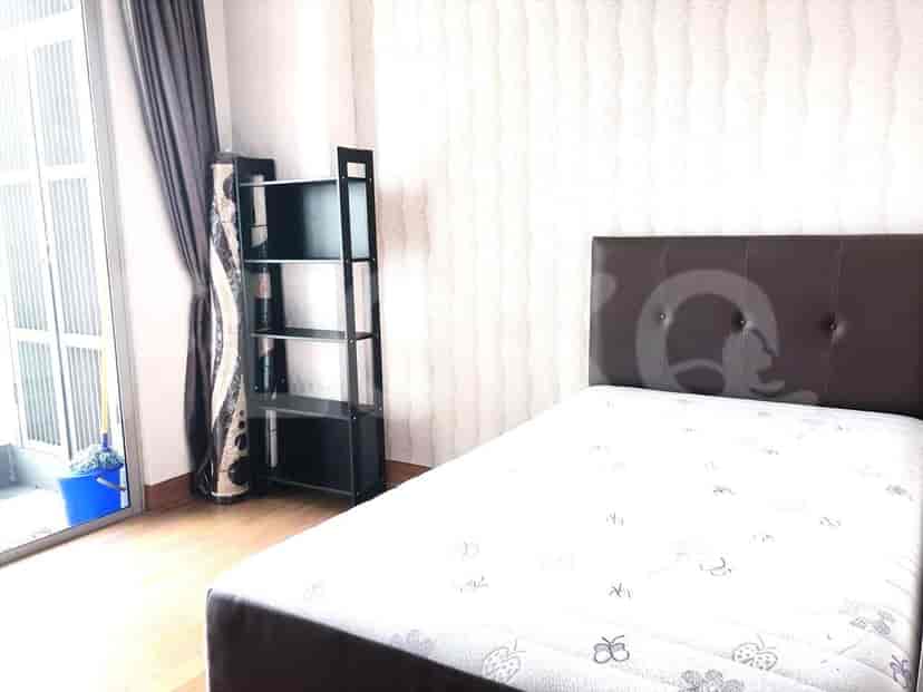 A bedroom featuring a single bed, a shelving unit, and a balcony door.