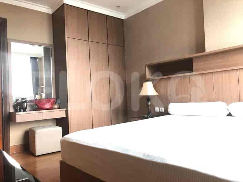 A bedroom with a large bed, a dresser, and wooden closet.
