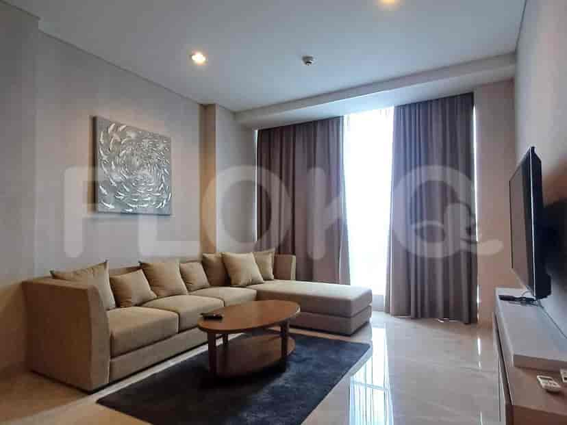 Ruang tamu modern menampilkan sofa berbentuk L, meja kopi, dan TV yang dipasang di dinding.
