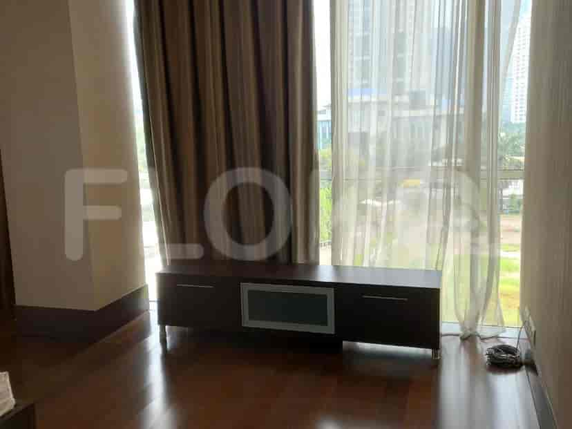 A bedroom featuring a flat-screen TV, curtains, and wooden flooring.